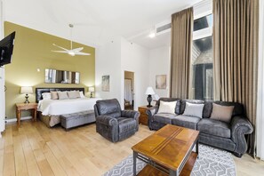 A modern hotel room with a bed, two sofas, a coffee table, and a ceiling fan.
