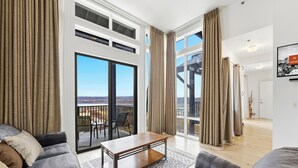 A spacious living room with a balcony, a large window, and a modern coffee table. - Top Floor Luxe Condo Near Deer Valley East, Minutes to  Lake, w/ Views, Hot Tub (Heber City)