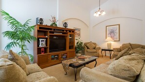 Ein Wohnzimmer mit einer Holz-Unterhaltungsecke, zwei beigen Sofas, einem Couchtisch und einer Lampe.