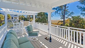 A covered outdoor deck with white railings, green cushioned seating, and a view of the beach and ocean. - A Perfect Day: Gulf Front! Rooftop Deck, Putt Putt, Pool Spa by Anna Maria Life (Anna Maria)