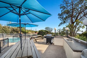 A deck with a barbecue grill, picnic tables, and a pool. - *Hot July Deal* Kona Mansions Ocean View (Kailua-Kona)
