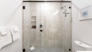 Une salle de bain moderne dotée d’une douche à parois de verre, de toilettes et d’un lavabo.