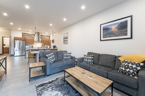 Ein modernes Wohnzimmer mit einem grauen Sofa, einem Holztisch und einem Teppich.
