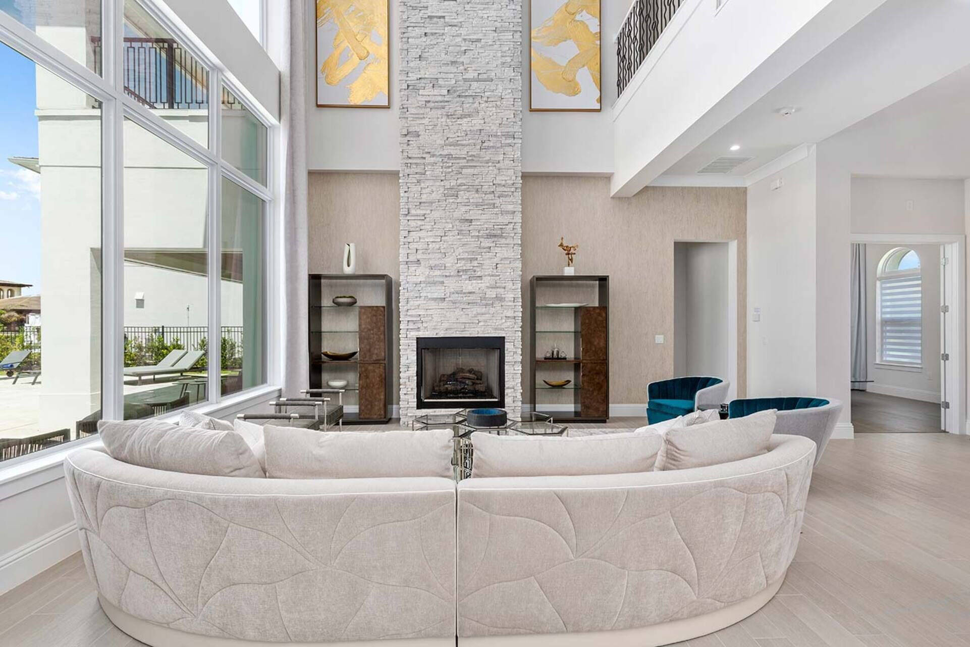 Un salon spacieux avec un grand canapé d’angle blanc, une cheminée et une vue sur le balcon extérieur.