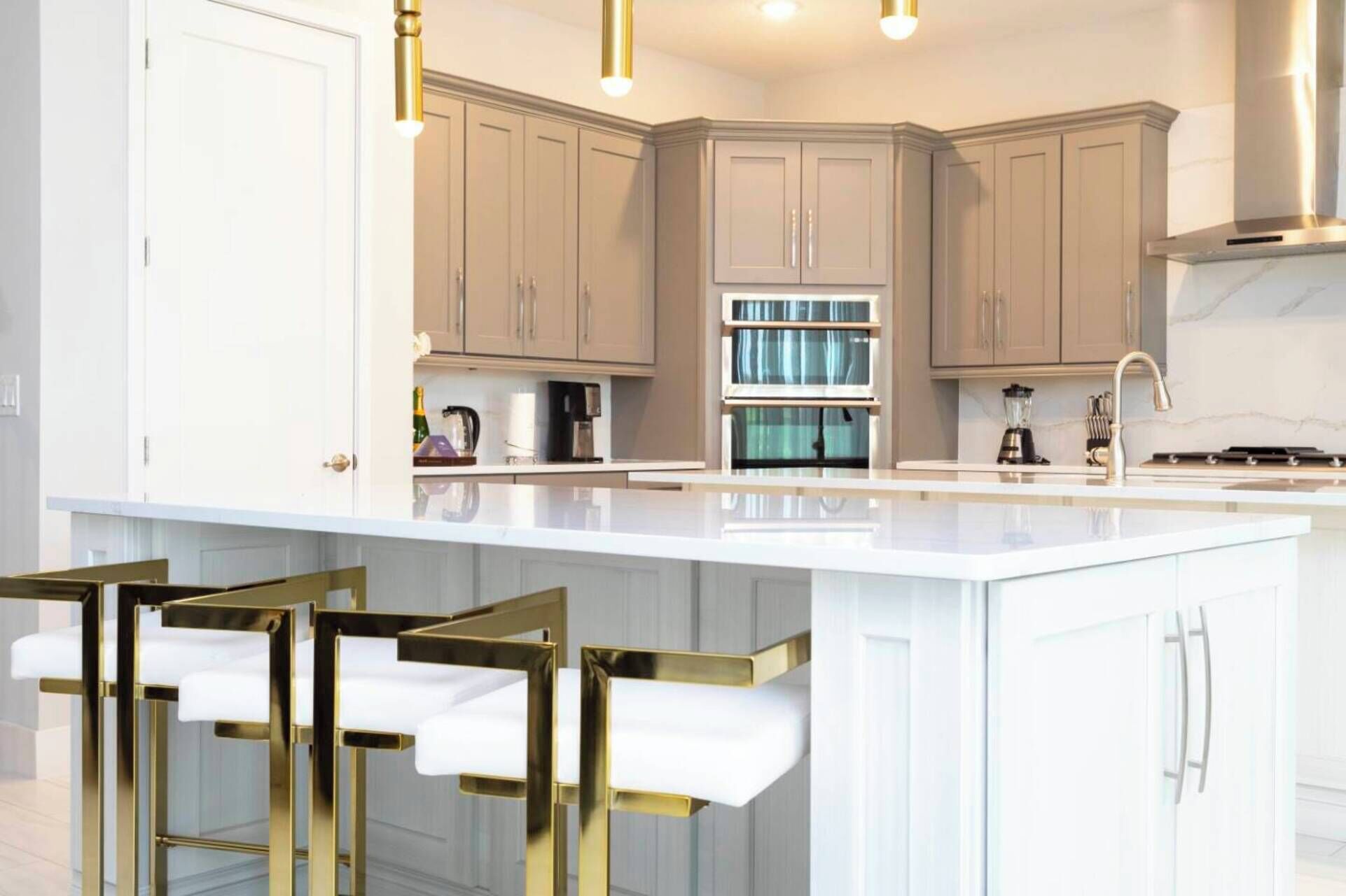A modern kitchen with white cabinetry, a central island with bar stools, and built-in appliances.