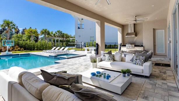 A modern outdoor living area with a pool, white furniture, and a barbecue setup. - 5 Star Villa Aurelius – A Golden Grand Residence (Orlando)
