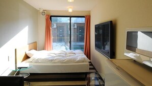 Une chambre d’hôtel avec un lit, une télévision et une fenêtre avec des rideaux.