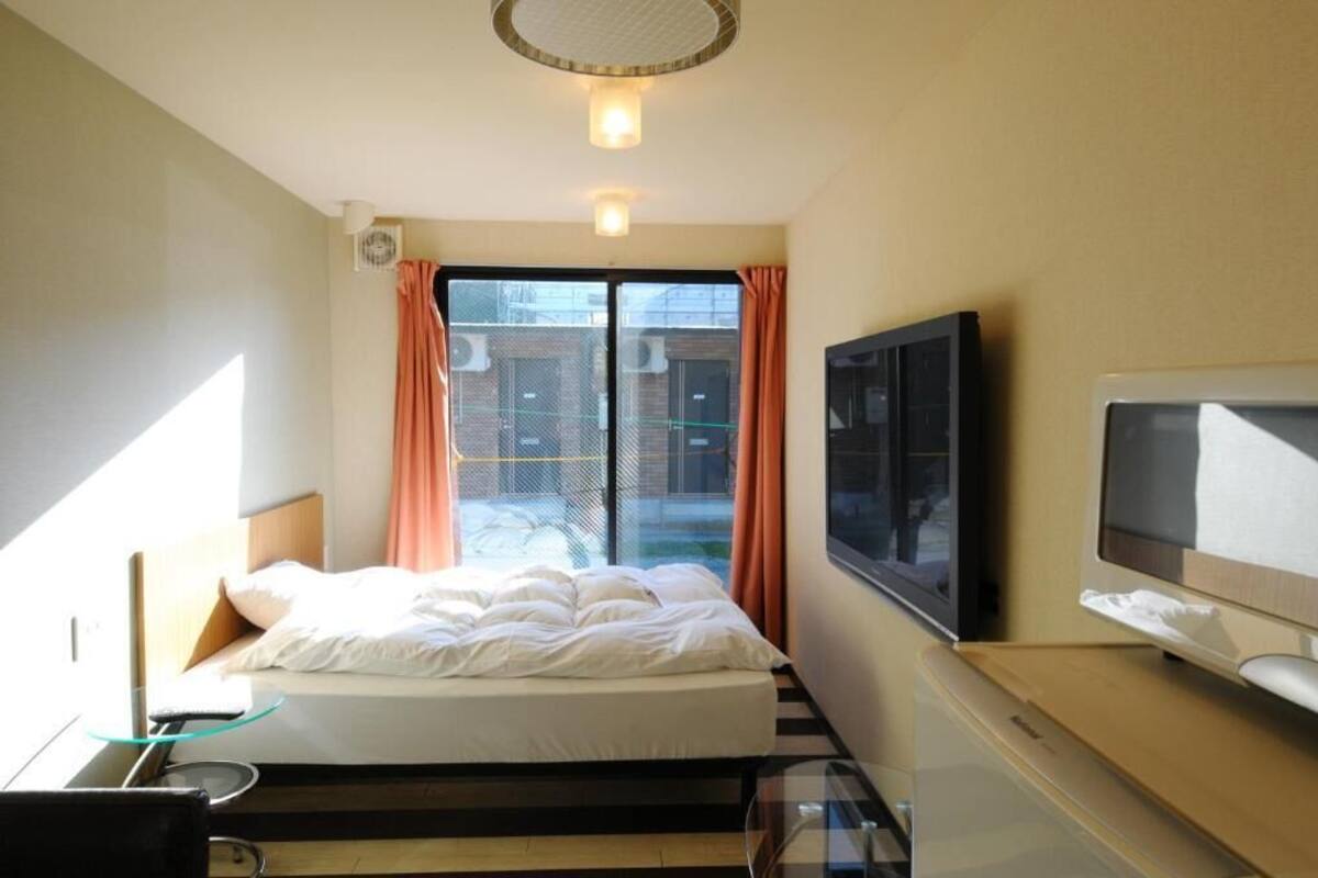 A hotel room with a bed, a television, and a window with curtains.