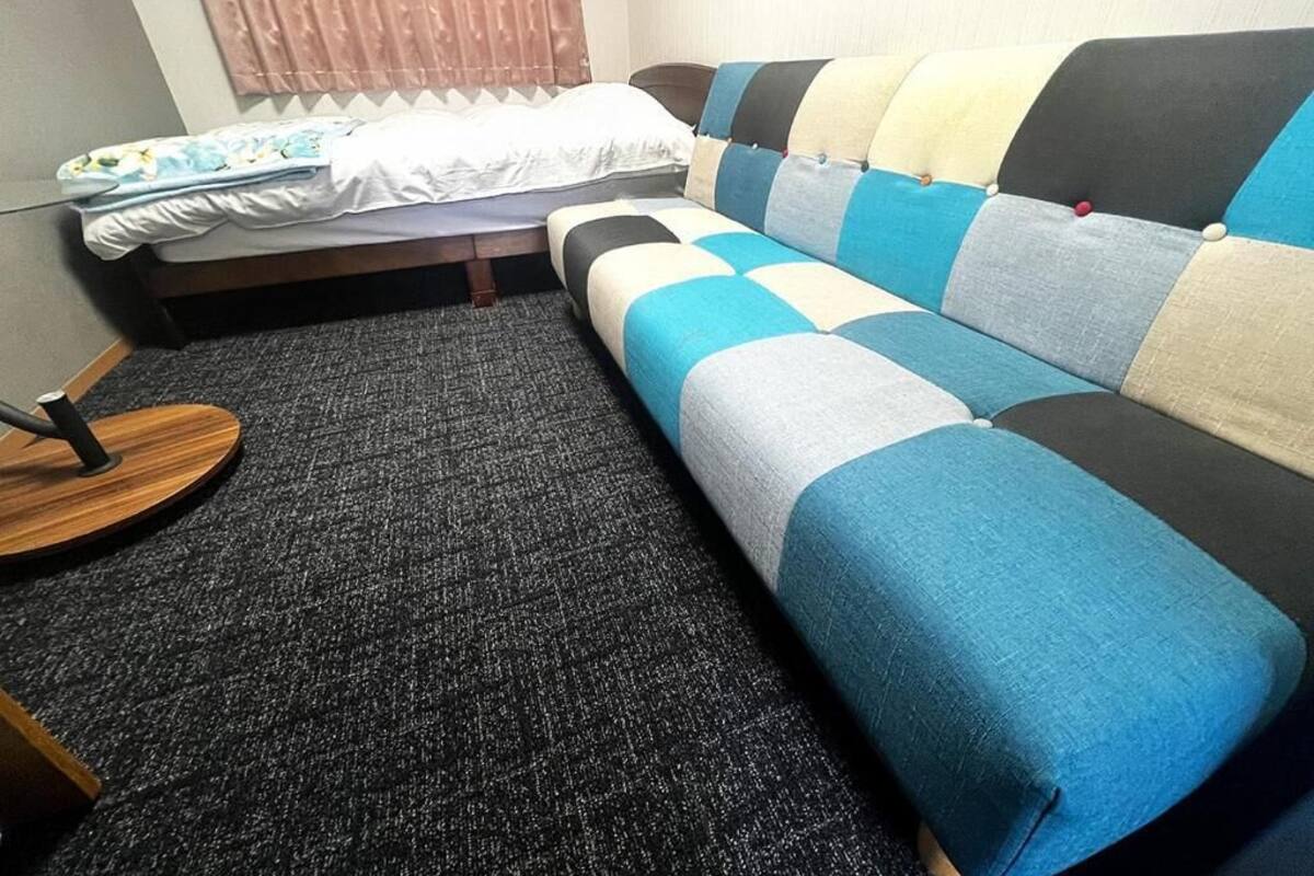 A room with a bed, a sofa, and a round wooden table.