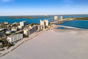 Un paisaje urbano costero con edificios altos, una playa y un puente.