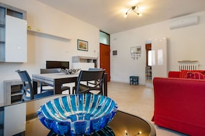 A modern living room with a red sofa, a glass coffee table, and a dining area with a table and chairs.