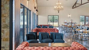Un'ampia sala da pranzo con una panca imbottita rossa, sedie blu e un lampadario.