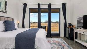 Una camera da letto con un letto, una televisione, una scrivania e vista su un campo.
