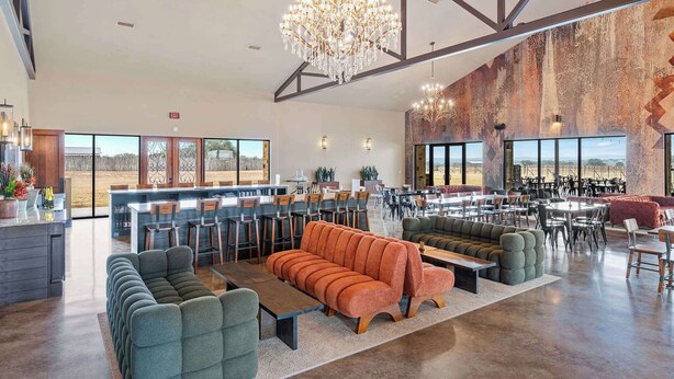 Spaziosa hall d'albergo con zona bar moderna, posti a sedere e ampie finestre che offrono vista sul deserto.
