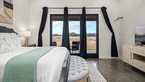 A bedroom with a bed, a chair, a TV, and a view of the outdoors. - Silverstone Casita 5 at Featherstone Ranch (Stonewall)