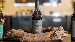 Una botella de vino Tannat de Featherstone Ranch sobre una superficie de madera, con un fondo desenfocado.