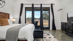 Ein Schlafzimmer mit einem Bett, einer Sitzbank, einem Fernseher und Blick ins Freie.