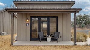 Un bâtiment doté d’un porche abrité, de deux chaises, d’une petite table et d’une enseigne indiquant le numéro 7.