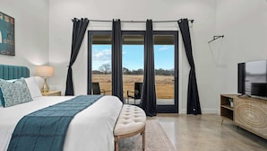 Une chambre dotée d’un grand lit, d’une télévision, d’une armoire en bois et offrant une vue sur l’extérieur grâce à une porte coulissante.