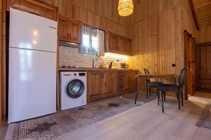 Ett kompakt kök med träskåp, ett kylskåp, en tvättmaskin och en matplats med ett bord och stolar.