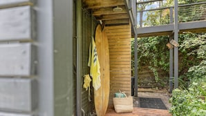 A wooden door with a towel hanging on the side, a surfboard leaning against the wall, and a woven basket on the ground. - NEW! The Soak House- Walk to the beach! (Lorne)