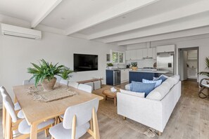 Een moderne woonkamer met een eethoek, een keuken en een kleine eettafel met stoelen.