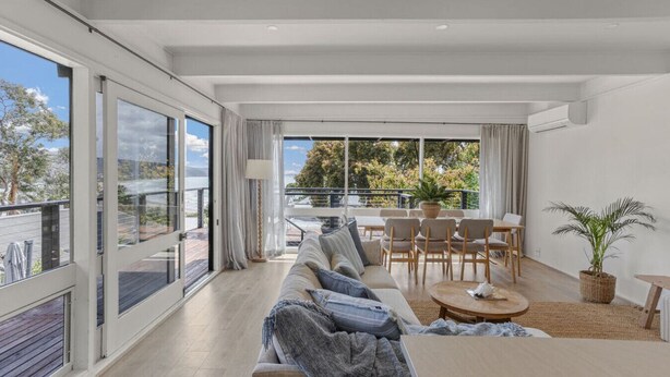 A modern living room with a sofa, chairs, a coffee table, and a balcony with a view. - NEW! The Soak House- Walk to the beach! (Lorne)