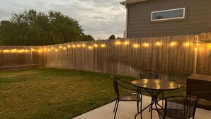 A backyard with a wooden fence, a concrete patio, and a table with chairs. - Spacious 2BR Flex Room Home Near Tech Campuses (Pflugerville)