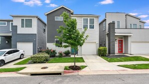 A row of modern townhouses with a central tree, a white car parked in front, and a well-maintained lawn. - Spacious 2BR Flex Room Home Near Tech Campuses (Pflugerville)