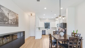 A modern kitchen with white cabinets, a dining table with chairs, and pendant lighting. - Spacious 2BR Flex Room Home Near Tech Campuses (Pflugerville)