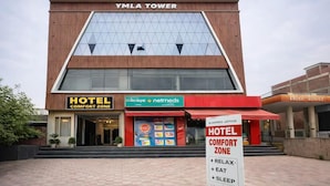 Un hôtel appelé « YMLA Tower », avec une enseigne indiquant « ZONE DE CONFORT », une pharmacie « netmeds » et une enseigne « HÔTEL ».