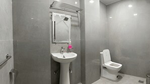 Une salle de bain moderne avec un lavabo sur colonne, des toilettes et un miroir au-dessus du lavabo.