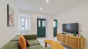 En moderne stue med en grøn sofa, et træbord og et fjernsyn på et træskab.