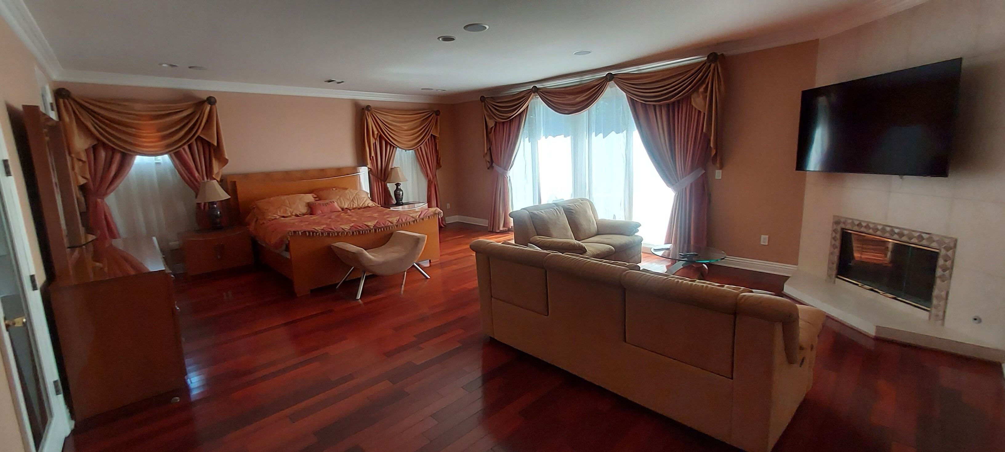 Habitación de hotel con una cama grande, un sofá, un televisor y una chimenea.