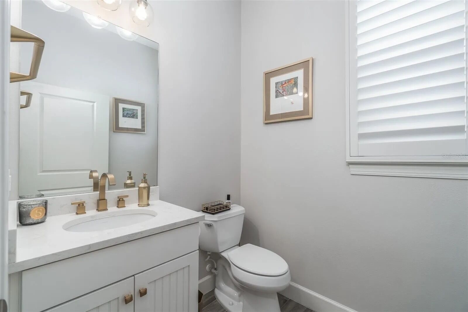 A bathroom with a white vanity, a toilet, and a framed picture on the wall.