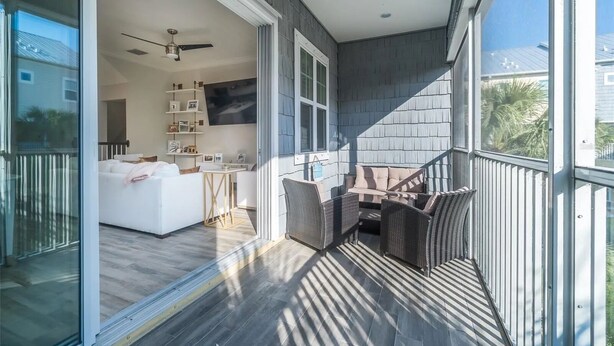 A modern living room with a white sofa, a dining table, and wicker chairs. - Waterfront Townhome w/ Garage – St. Pete (St. Petersburg)
