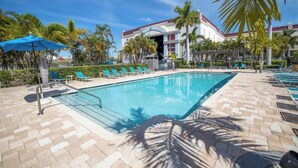 A swimming pool with lounge chairs and palm trees. - Waterfront Townhome w/ Garage – St. Pete (St. Petersburg)