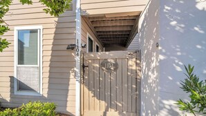 Ett hus i beige med en träport, en brevlåda och en liten trädgårdsyta.