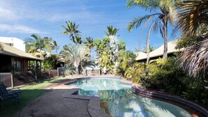 Ein Pool, umgeben von Palmen und einer überdachten Terrasse.