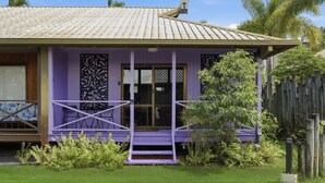 Ein eingeschossiges Gebäude mit violetten Fassade, einem Ziegeldach und einer kleinen Veranda mit Geländer.
