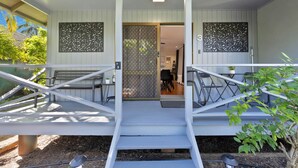 Un espace extérieur abrité, doté d’un escalier menant à une porte, d’un banc et d’une petite table.