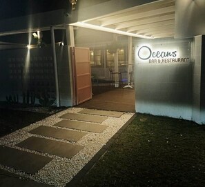 A bar and restaurant named 'Oceans' with a wooden deck and a gravel pathway leading to the entrance.