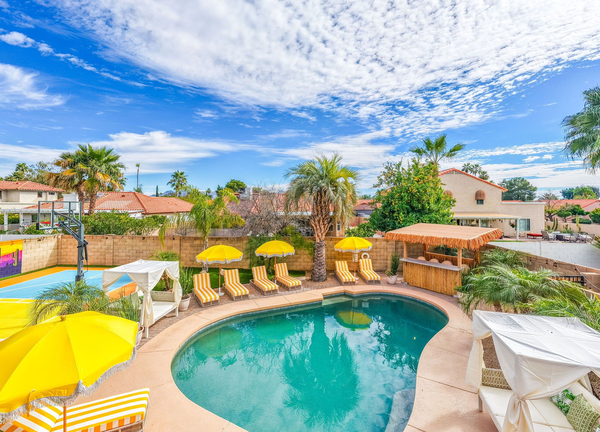 A backyard with a swimming pool, lounge chairs, and umbrellas.