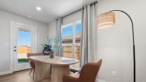A modern dining area with a wooden table, two brown chairs, a vase with plants, and a floor lamp. - Wellness Retreat - 3BR/2BA - Family Friendly (Lubbock)