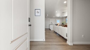 A hallway with a wooden floor leading to a kitchen area with a white countertop and a sink. - Wellness Retreat - 3BR/2BA - Family Friendly (Lubbock)