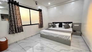 A bedroom with a bed, curtains, a window, and a tiled floor. - Soneva Hotel (Ahmedabad)