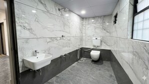 A modern bathroom with a marble wall, a sink, a toilet, and a shower. - Soneva Hotel (Ahmedabad)