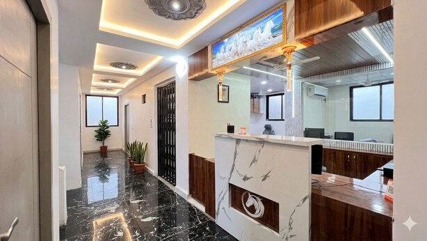 A reception area with a marble counter, a framed artwork above it, and a potted plant in the hallway. - Soneva Hotel (Ahmedabad)