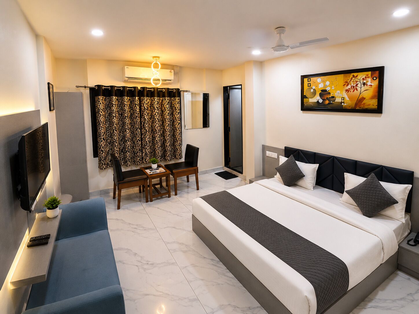Quarto de hotel moderno com uma cama grande, televisão de tela plana, escrivaninha com cadeira e um quadro na parede.