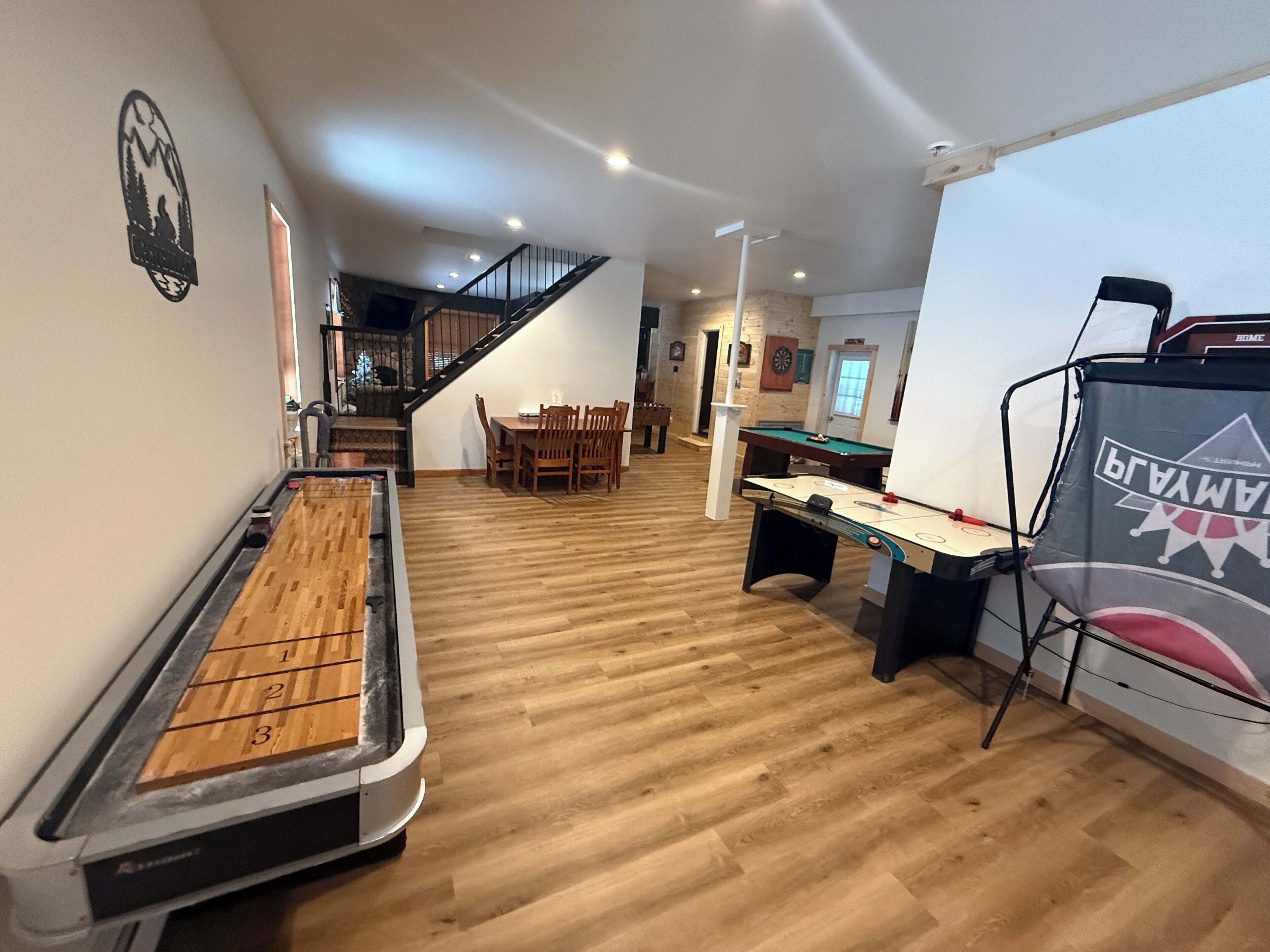 A billiards room with a pool table, a foosball table, and a dartboard.